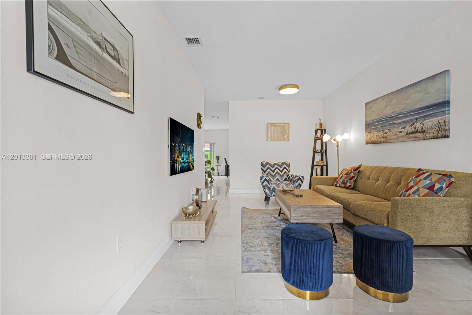 A living room features a tan sofa, blue ottomans, a coffee table, and tiled floors — 9354 SW 220th St, Cutler Bay FL 33190, CUTLER BAY, FL
