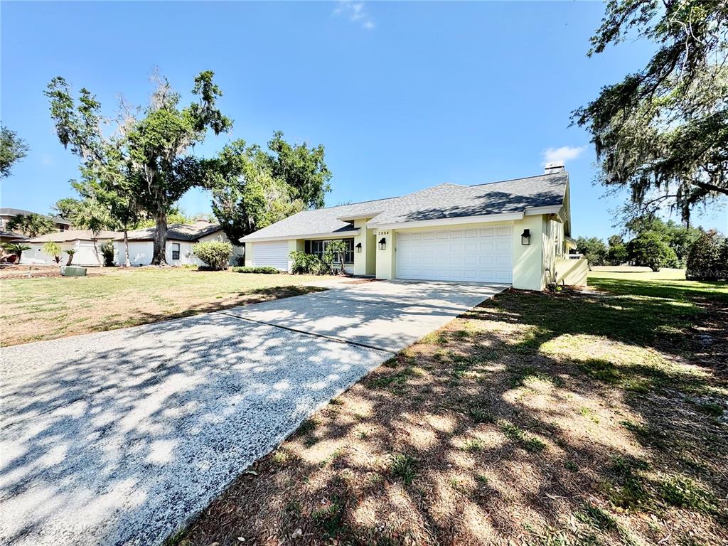 A single-story house with a light-colored exterior, a two-car garage, and a concrete driveway — 2804 WEDGEWOOD DRIVE, PLANT CITY, FL