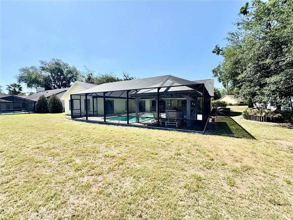 A backyard view of a house with a screened-in swimming pool and patio area — 2804 WEDGEWOOD DRIVE, PLANT CITY, FL