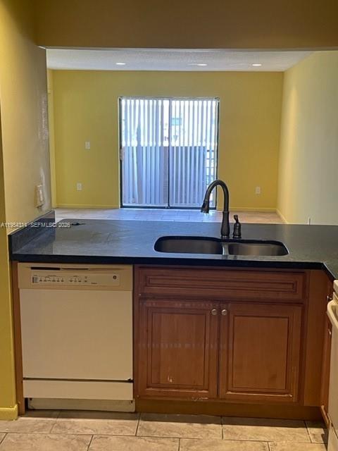 A kitchen with a white dishwasher, dark countertops, and wooden cabinets overlooks a living area — 20815 NE 8th Ct # 20, Miami FL 33179, MIAMI, FL