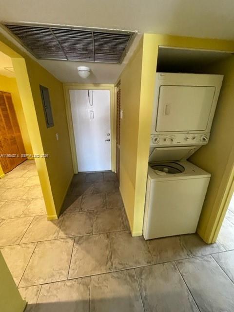 A hallway with tile floors leads to a white door next to a stacked washer-dryer unit — 20815 NE 8th Ct # 20, Miami FL 33179, MIAMI, FL