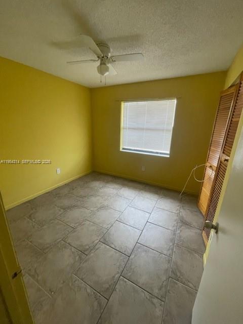 A bedroom with yellow walls, a ceiling fan, tiled floors, and a louvered closet door — 20815 NE 8th Ct # 20, Miami FL 33179, MIAMI, FL