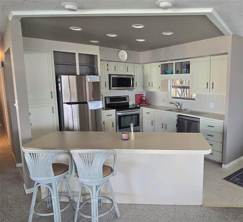 A kitchen features light-colored cabinetry, stainless steel appliances, a breakfast bar, and recessed lighting — 271 COLONIAL BOULEVARD UNIT 11, PALM HARBOR, FL