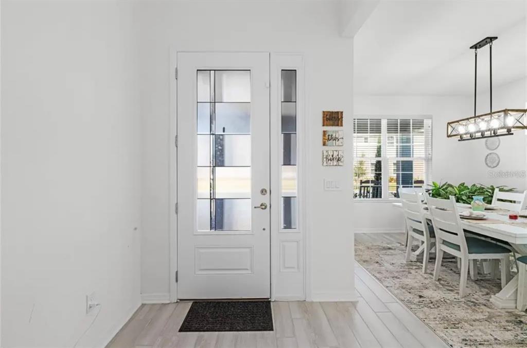 A white front door with glass panels opens into a dining room with light flooring — 826 TERRAPIN DRIVE, DEBARY, FL