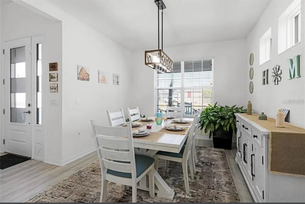 A dining room features a white table with six chairs, a chandelier, and a sideboard — 826 TERRAPIN DRIVE, DEBARY, FL