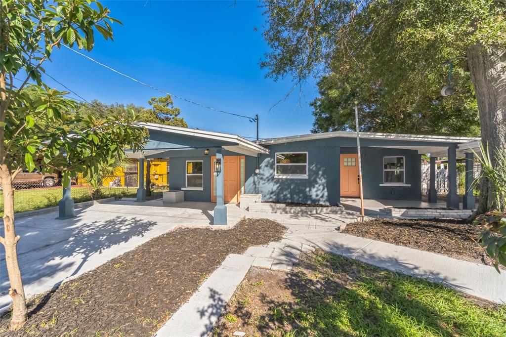 A blue single-story house with a carport, two orange doors, and a concrete walkway — 5210 S 84TH STREET, TAMPA, FL