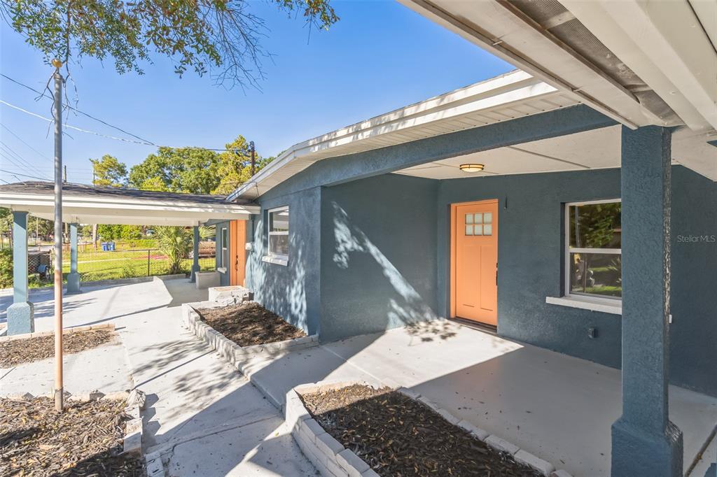 A blue house exterior features a covered porch, a peach-colored door, and concrete planters — 5210 S 84TH STREET, TAMPA, FL