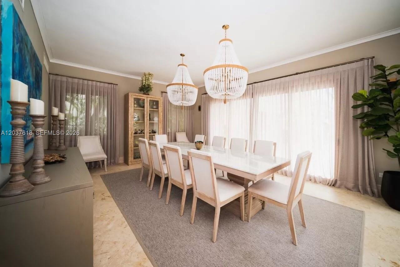A dining room features a long table with ten chairs, two beaded chandeliers, and floor-to-ceiling curtains — 0 La Palmas, FL, FL