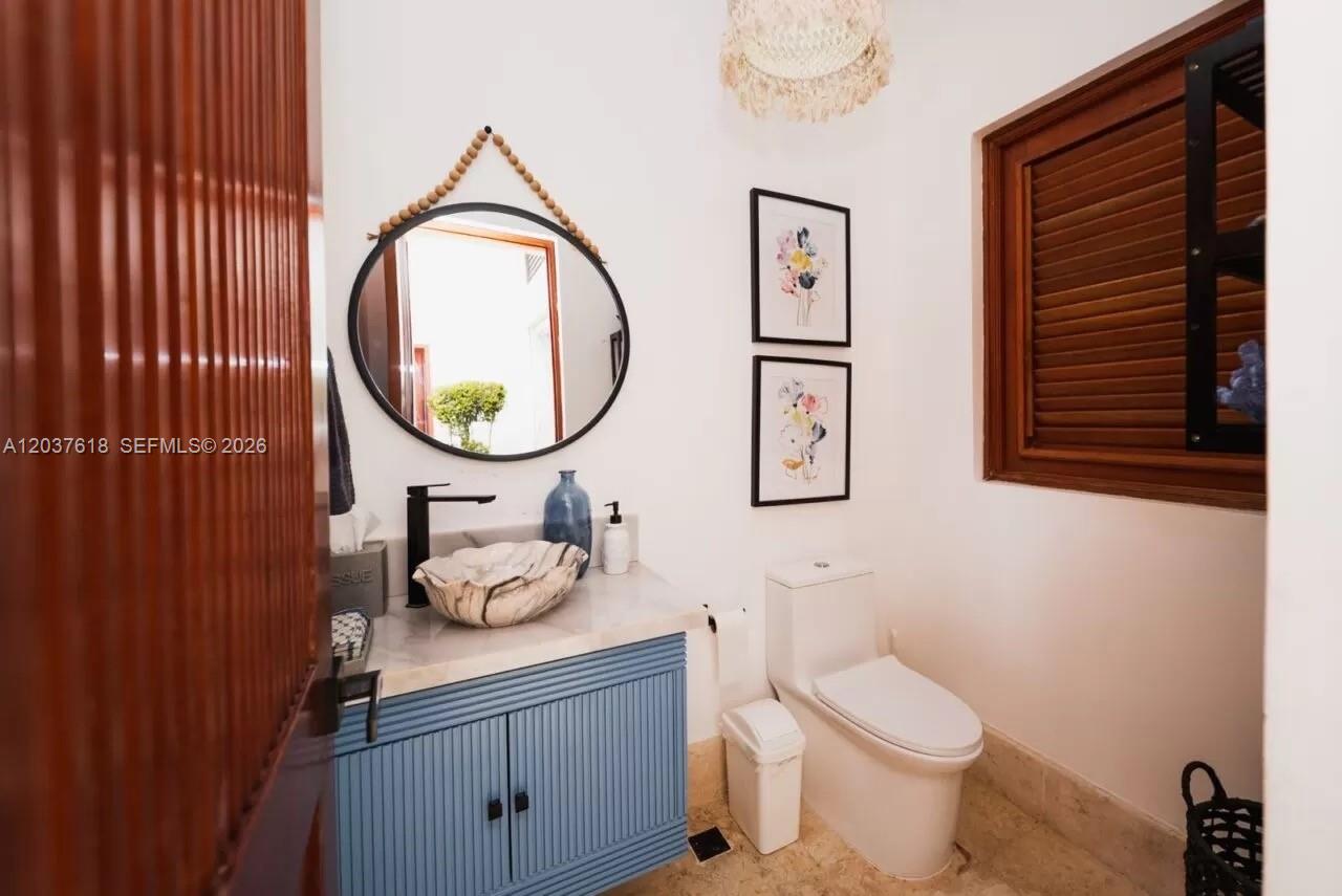A bathroom features a blue vanity, a marble vessel sink, and a round wall mirror — 0 La Palmas, FL, FL
