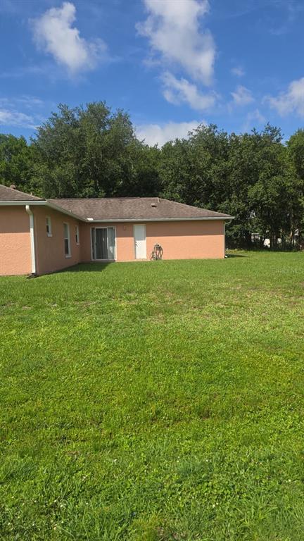 A peach-colored house exterior with a sliding glass door and a white door — 202 CHADWORTH DRIVE, KISSIMMEE, FL