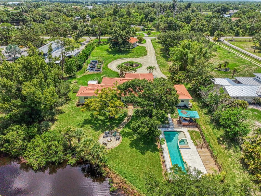 An aerial view shows a house with a red tile roof, pool, and waterfront backyard — 140 S OXFORD DRIVE, ENGLEWOOD, FL