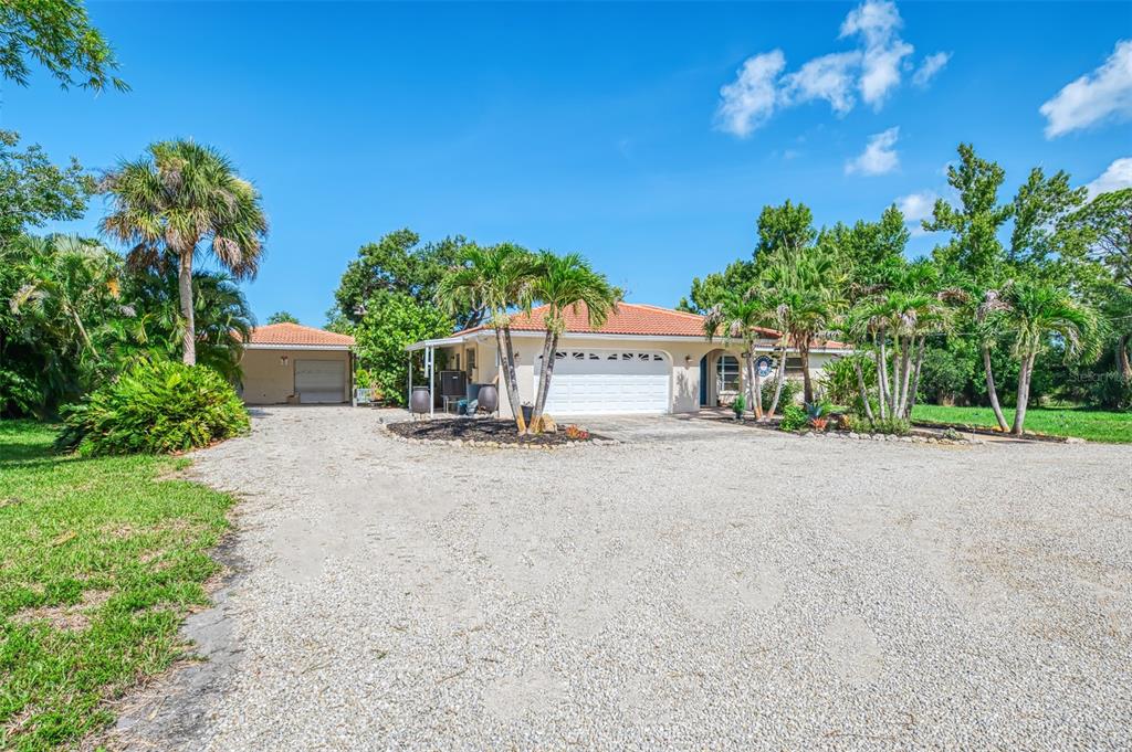 A single-story house with a gravel driveway, a two-car garage, and several palm trees — 140 S OXFORD DRIVE, ENGLEWOOD, FL