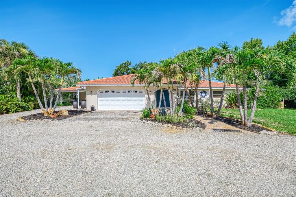 A single-story house with a white garage, tiled roof, and palm trees in the front yard — 140 S OXFORD DRIVE, ENGLEWOOD, FL