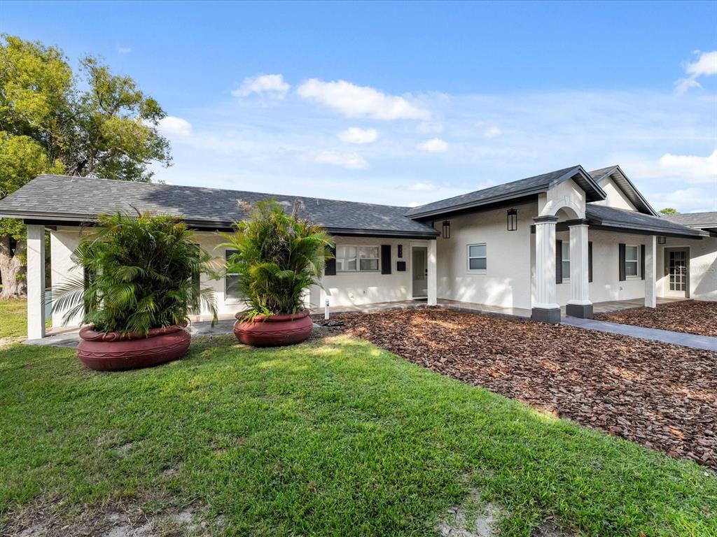 A single-story white house with a dark roof, two large potted palms, and mulch landscaping — 329 SEMINOLA BOULEVARD, CASSELBERRY, FL