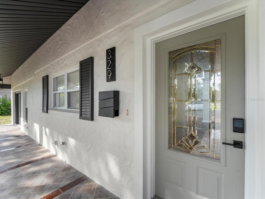 A covered porch with a tiled floor leads to a gray front door with glass — 329 SEMINOLA BOULEVARD, CASSELBERRY, FL