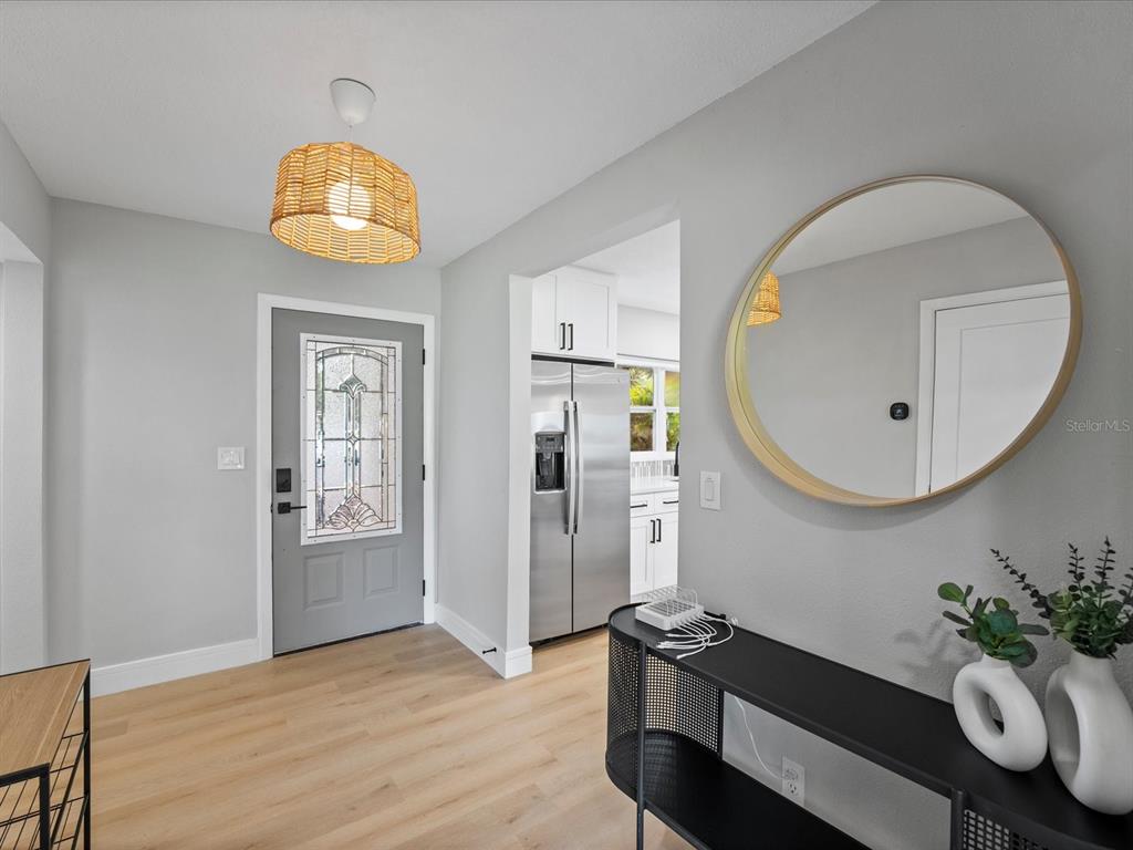 An entryway features light wood flooring, a gray front door, and a round gold mirror — 329 SEMINOLA BOULEVARD, CASSELBERRY, FL