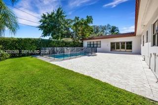 A backyard features a swimming pool with a safety fence, a patio, and green lawn — 712 Cremona Ave, Coral Gables FL 33146, CORAL GABLES, FL