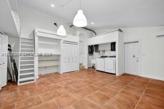 A room with terracotta tile floors, built-in shelving, a ladder, and a laundry area — 712 Cremona Ave, Coral Gables FL 33146, CORAL GABLES, FL