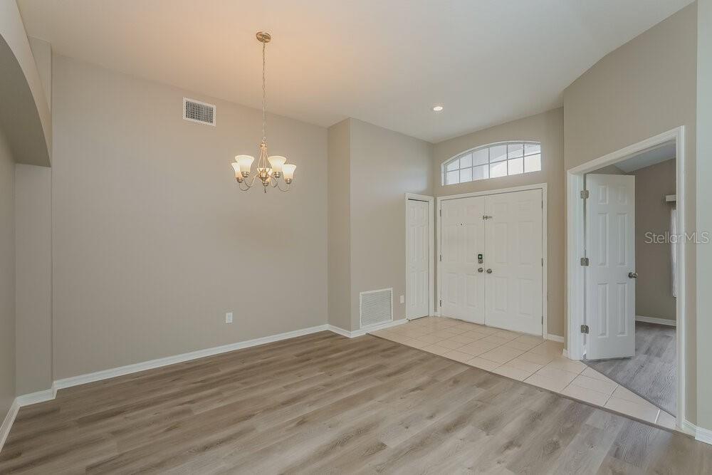 An entryway with light-colored walls, wood-look flooring, a chandelier, and a white double door — 411 SAND RIDGE DRIVE, VALRICO, FL