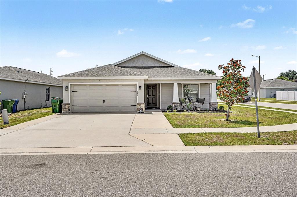 A single-story house with a two-car garage, stone accents, and a covered front porch — 647 LORIENT DRIVE, EAGLE LAKE, FL