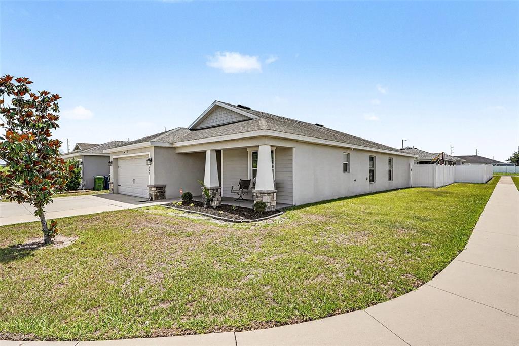 A single-story house with a beige stucco exterior, a two-car garage, and a covered porch — 647 LORIENT DRIVE, EAGLE LAKE, FL