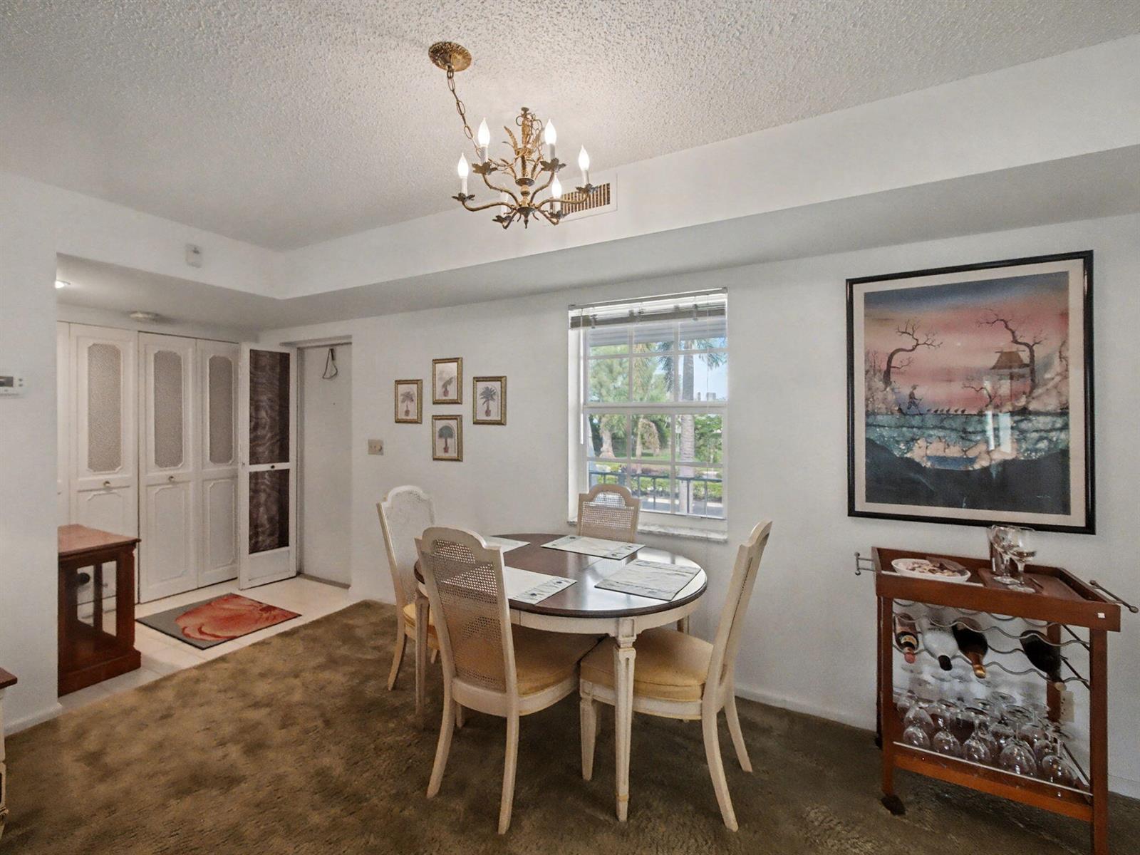 A dining area features a round table, four chairs, a chandelier, and a bar cart — 1205 Sandy Lane # 246, Singer Island FL 33404, SINGER ISLAND, FL