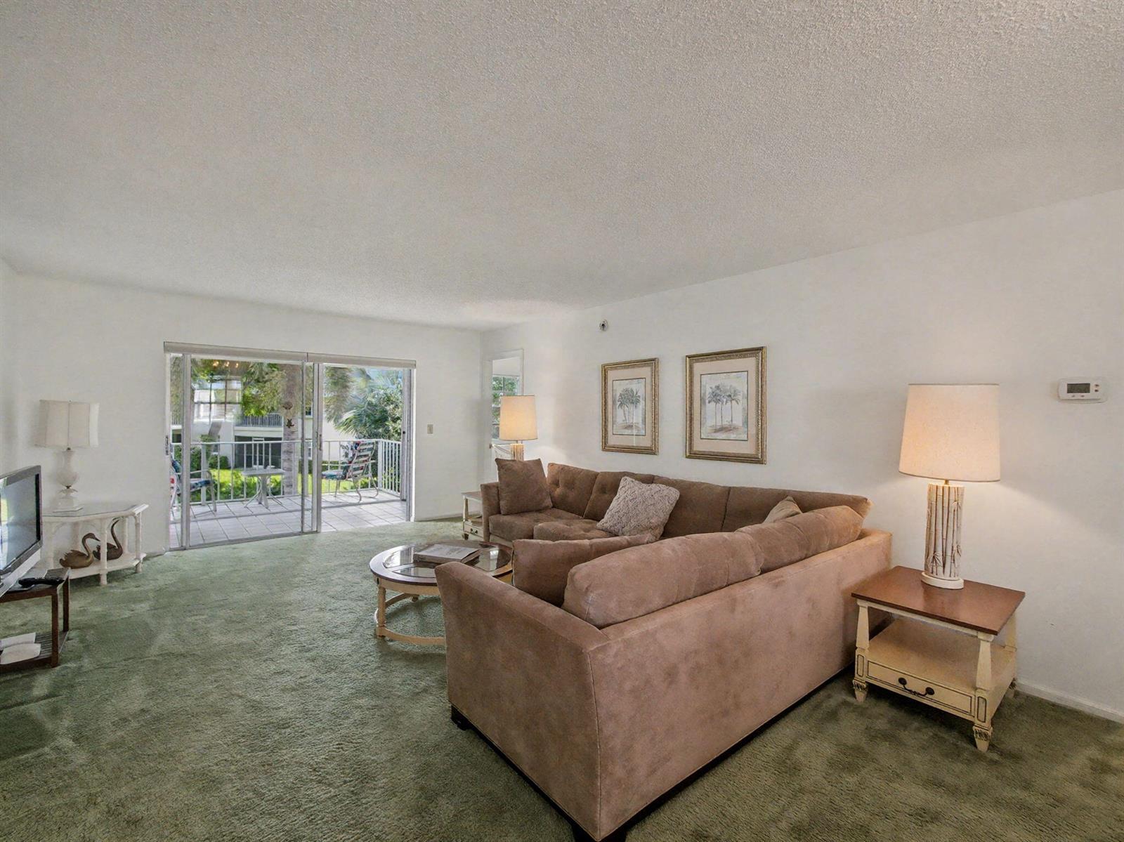 A living room features green carpet, a brown sectional sofa, and a sliding glass door — 1205 Sandy Lane # 246, Singer Island FL 33404, SINGER ISLAND, FL