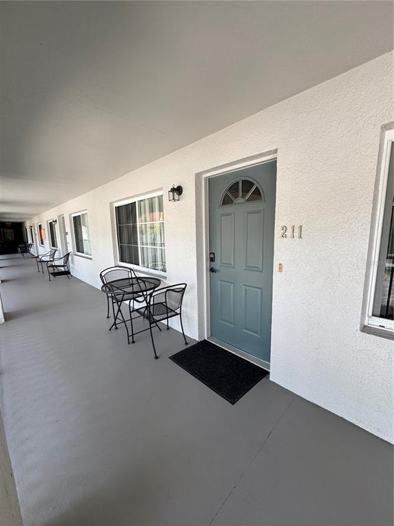 An exterior walkway features a blue door numbered 211, a small table, and two chairs — 4457 W 45TH AVENUE UNIT 211, BRADENTON, FL