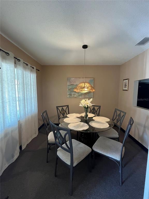 A dining room features a glass-topped table, six chairs, and a woven pendant light fixture — 4457 W 45TH AVENUE UNIT 211, BRADENTON, FL