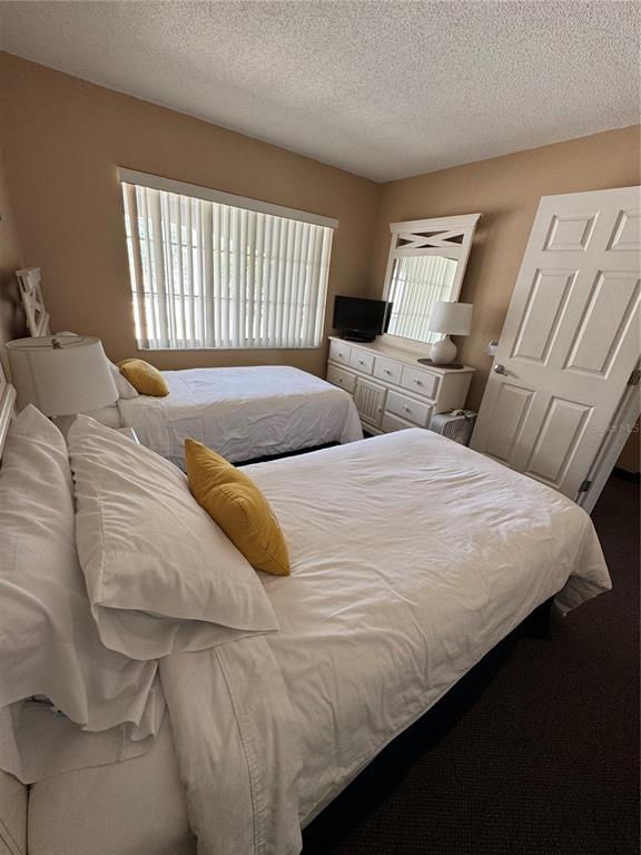 A bedroom with two twin beds, a dresser with a mirror, and a window — 4457 W 45TH AVENUE UNIT 211, BRADENTON, FL