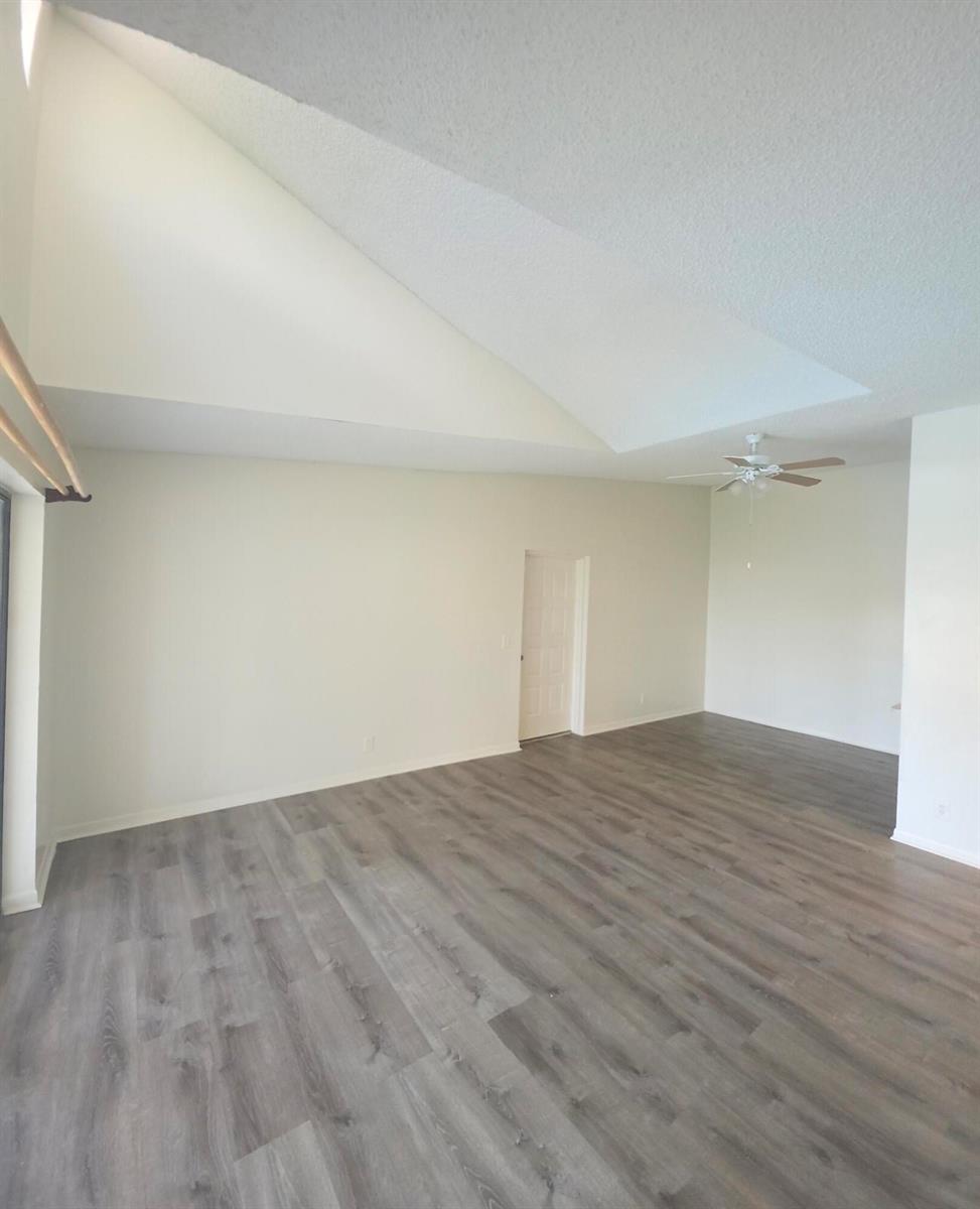 An empty room with vaulted ceilings, light-colored walls, and gray wood-look flooring — 202 Foxtail Drive # F3, FL 33415, FL