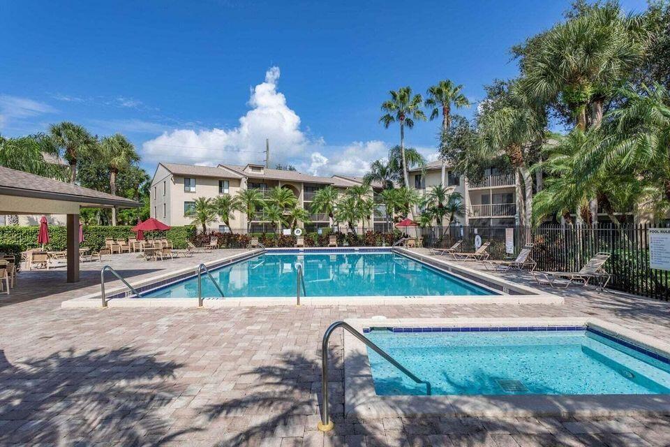 A swimming pool and hot tub are surrounded by a paved deck and apartment buildings — 202 Foxtail Drive # F3, FL 33415, FL