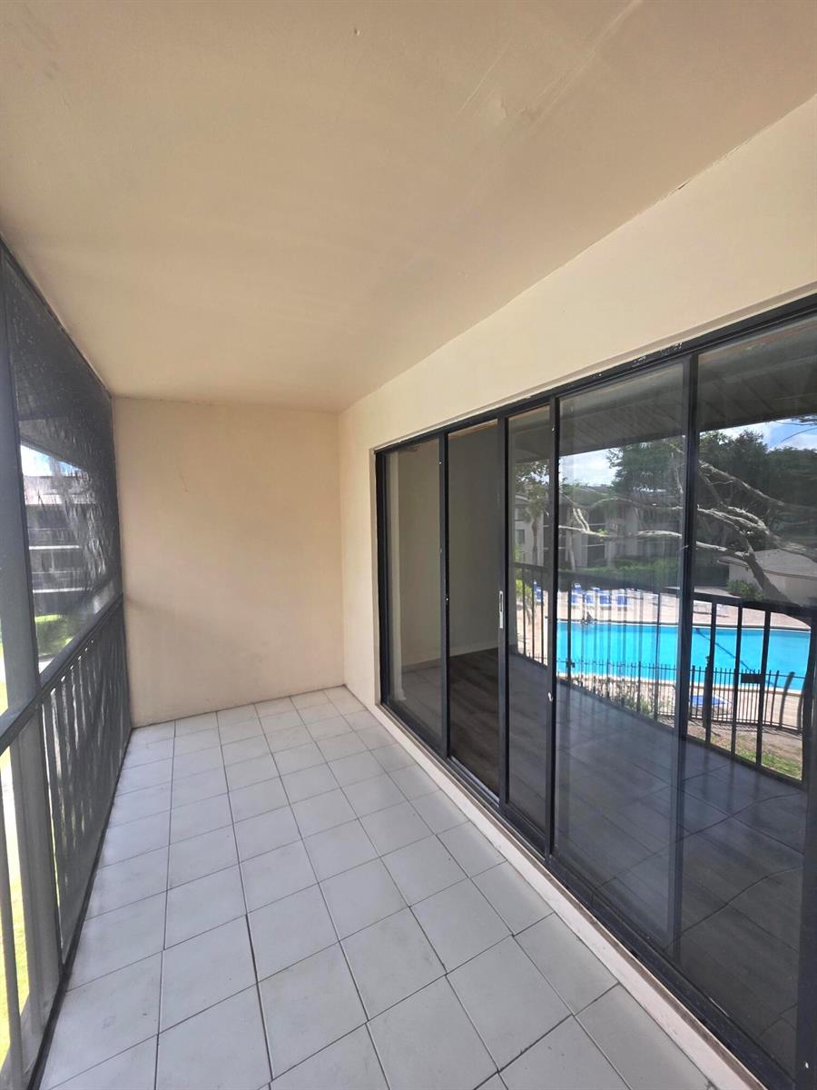 A screened-in balcony with white tile flooring overlooks a swimming pool — 202 Foxtail Drive # F3, FL 33415, FL