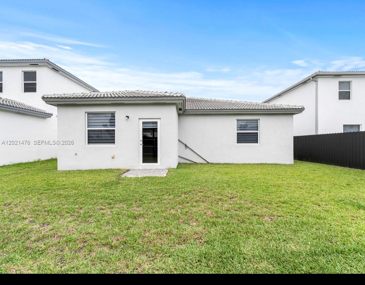 The exterior rear view of a white stucco house features a glass door and windows — 14884 SW 162nd St, Miami FL 33187, MIAMI, FL