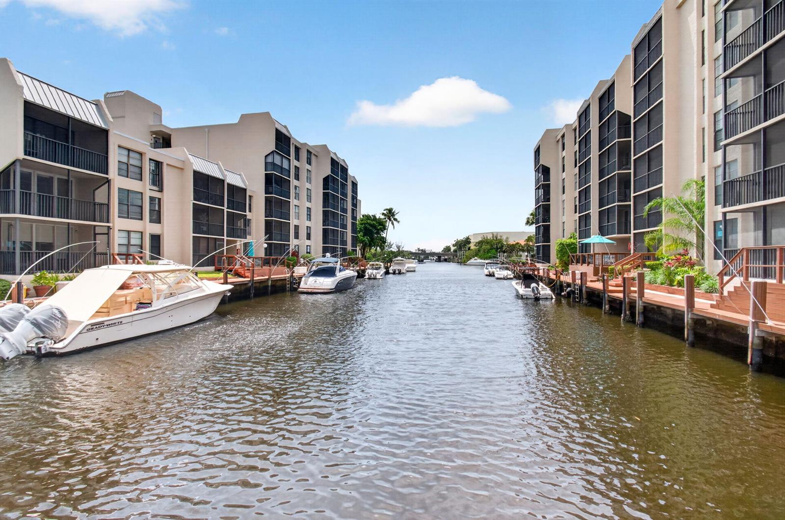 A canal lined with multi-story apartment buildings and private boat docks under a blue sky — 12 Royal Palm Way # 501, Boca Raton FL 33432, BOCA RATON, FL