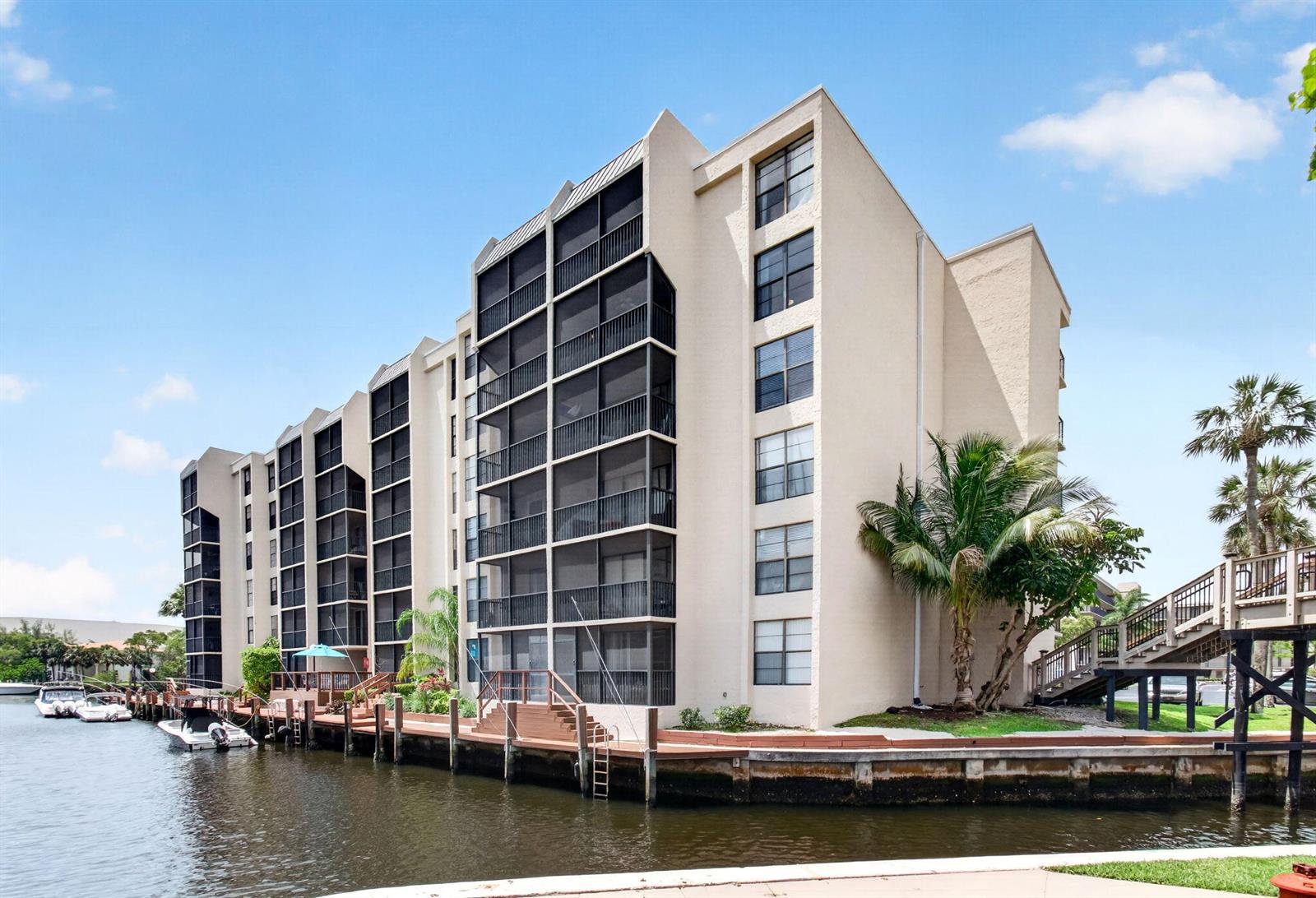A multi-story apartment building with screened balconies sits along a canal with docked boats — 12 Royal Palm Way # 501, Boca Raton FL 33432, BOCA RATON, FL