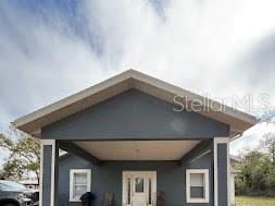 A dark gray house exterior features a large covered front porch with white trim — 7040 LUMBERTON ROAD, ZEPHYRHILLS, FL