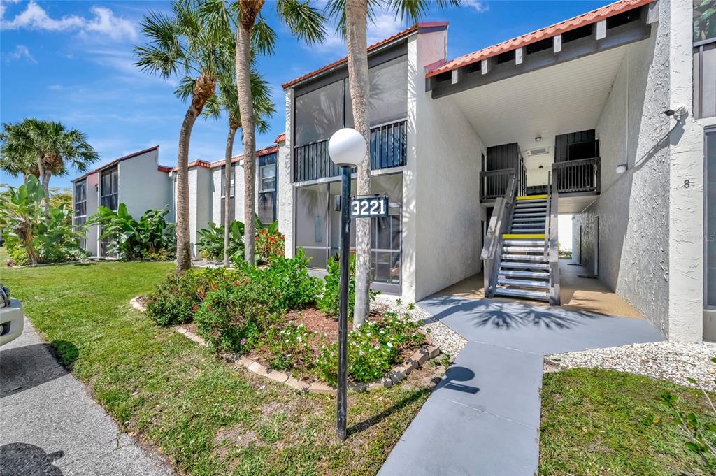 An exterior view of a two-story apartment building with a staircase and palm trees — 3221 BENEVA ROAD UNIT 102, SARASOTA, FL