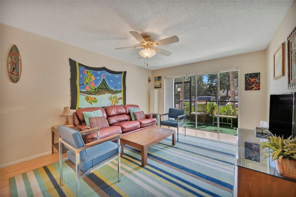 A living room features a leather sofa, blue chairs, a striped rug, and sliding doors — 3221 BENEVA ROAD UNIT 102, SARASOTA, FL