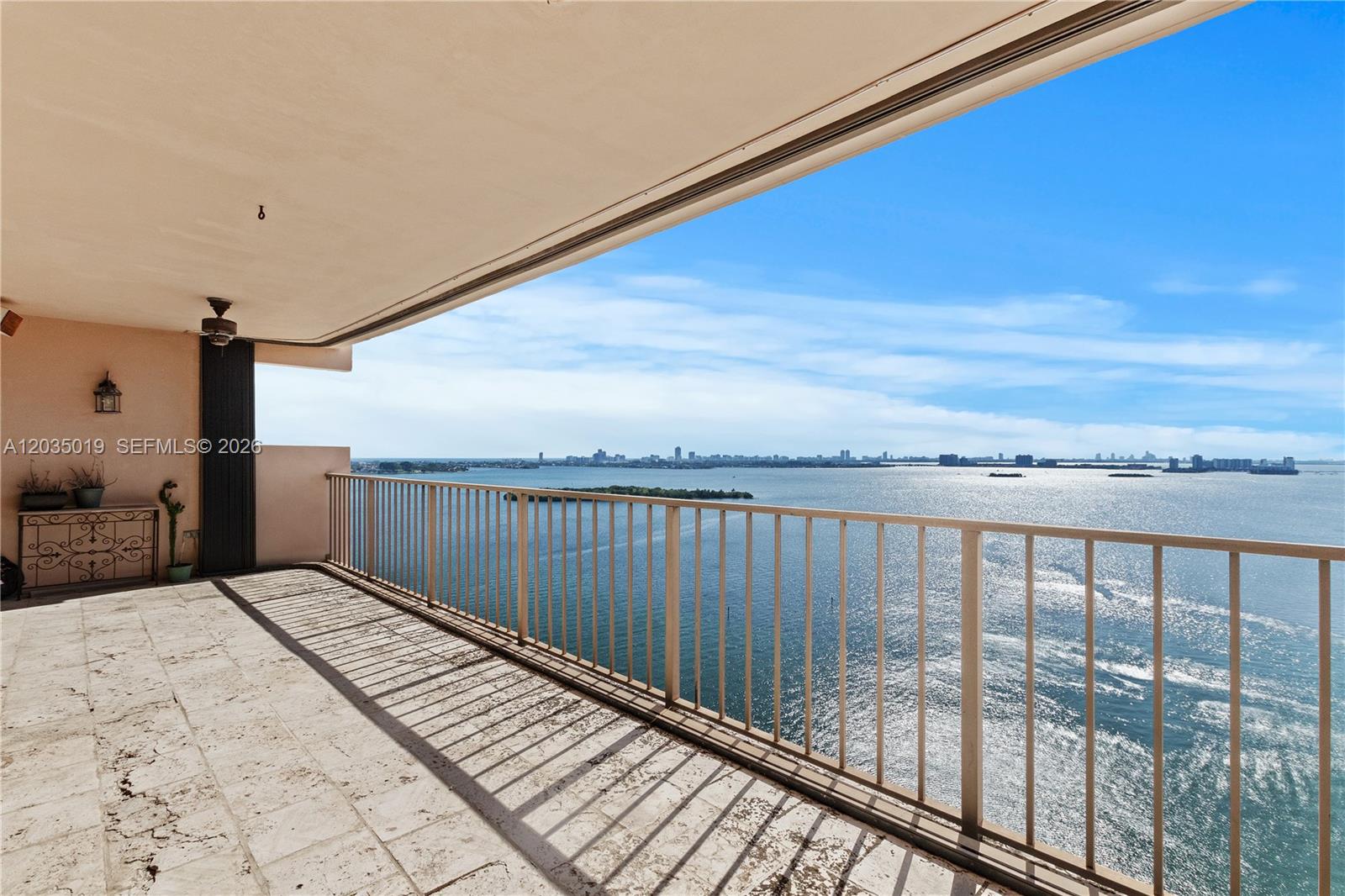 A spacious balcony features light stone flooring, a metal railing, and panoramic water views — 1800 NE 114th St # 2204, Miami FL 33181, MIAMI, FL