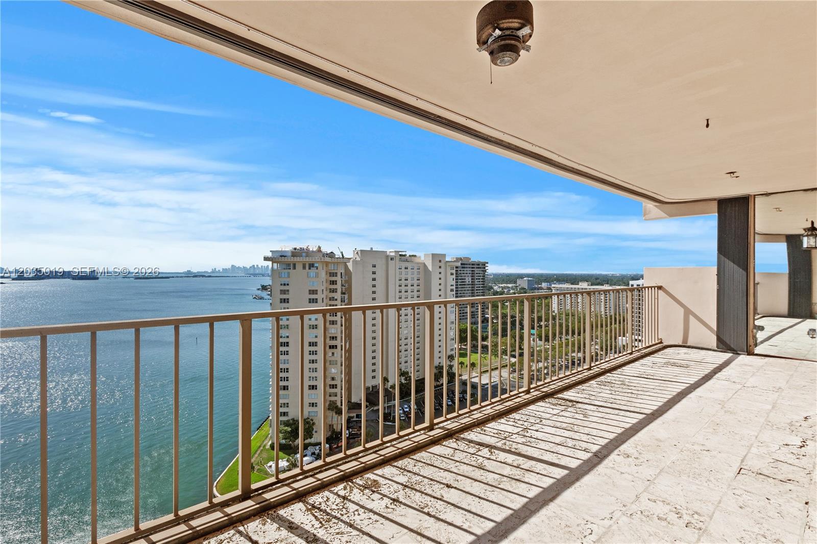 A balcony with a metal railing overlooks a large body of water and city buildings — 1800 NE 114th St # 2204, Miami FL 33181, MIAMI, FL
