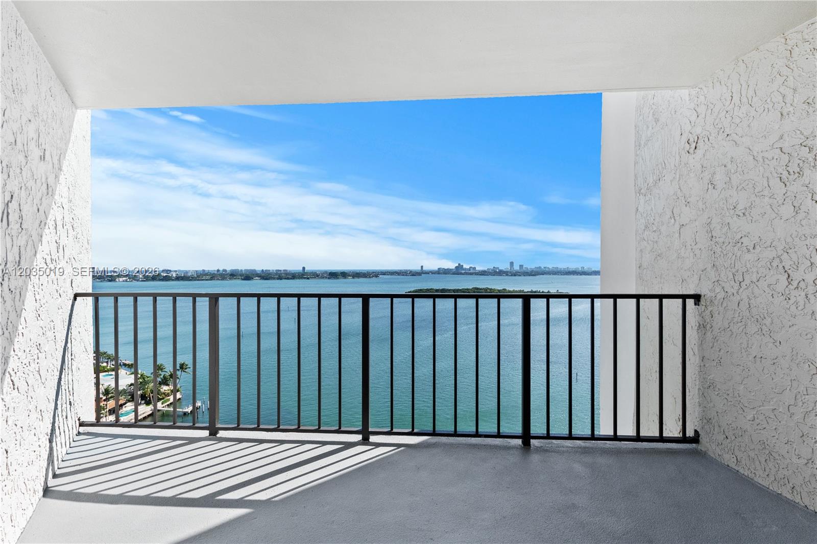 A balcony with a black metal railing overlooks a wide bay and distant city skyline — 1800 NE 114th St # 2204, Miami FL 33181, MIAMI, FL