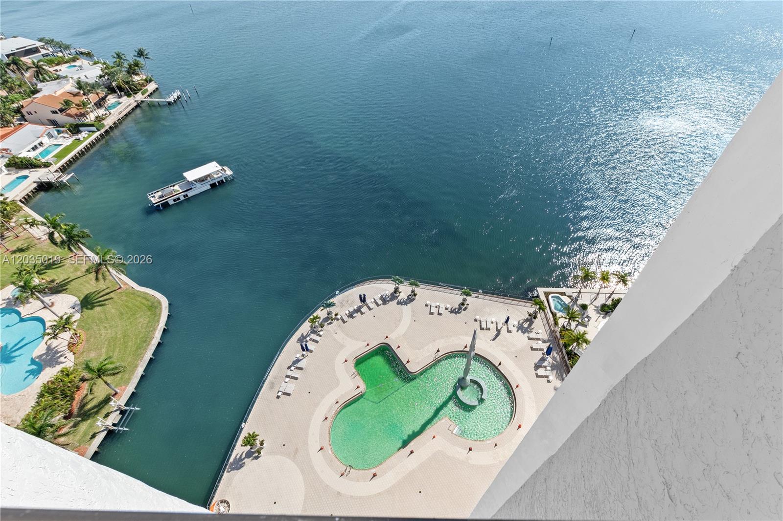 An aerial view shows a swimming pool with a fountain beside a waterfront building — 1800 NE 114th St # 2204, Miami FL 33181, MIAMI, FL