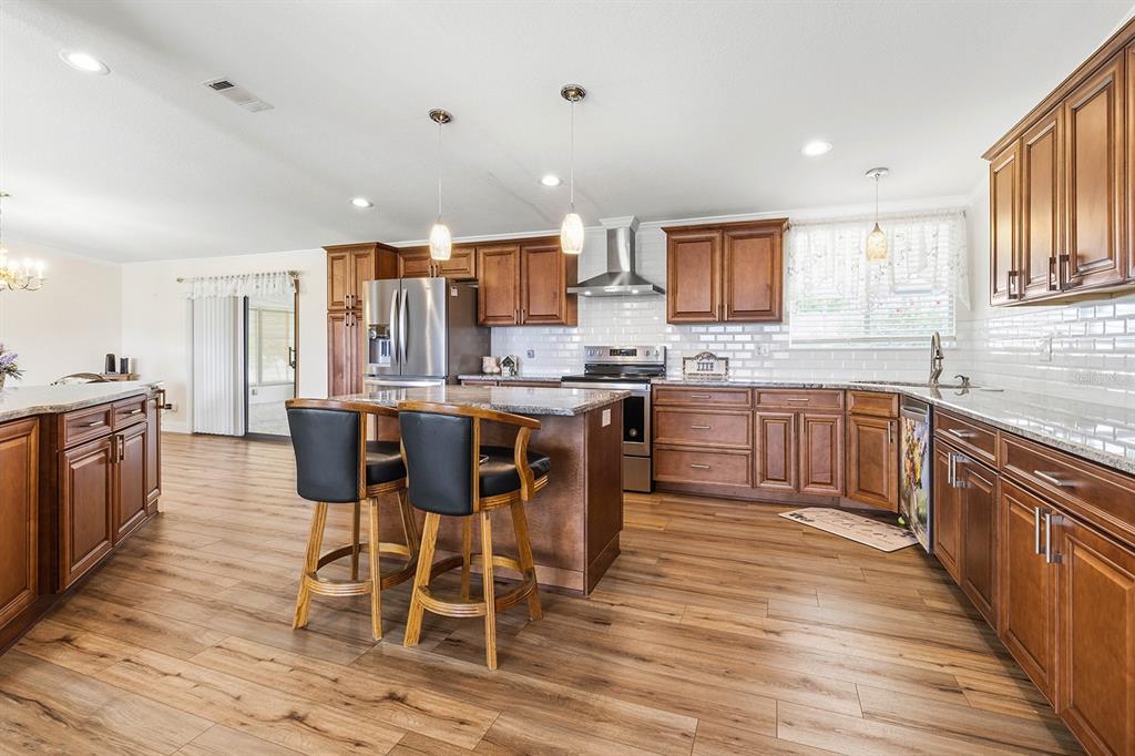 A kitchen features wood cabinets, granite countertops, stainless steel appliances, and a central island — 5230 REVELATION DRIVE, POLK CITY, FL
