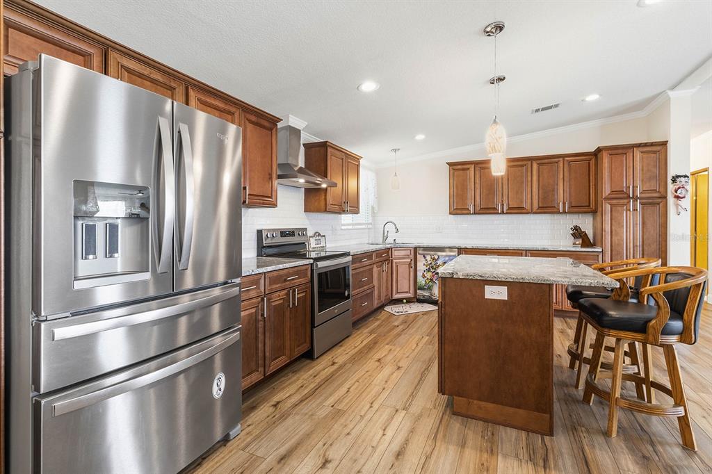 A kitchen features wood cabinets, stainless steel appliances, granite countertops, and a central island — 5230 REVELATION DRIVE, POLK CITY, FL