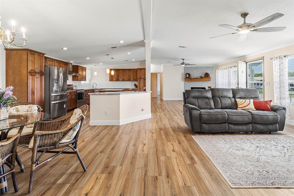 An open-concept living room and kitchen featuring wood-look flooring and a gray reclining sofa — 5230 REVELATION DRIVE, POLK CITY, FL