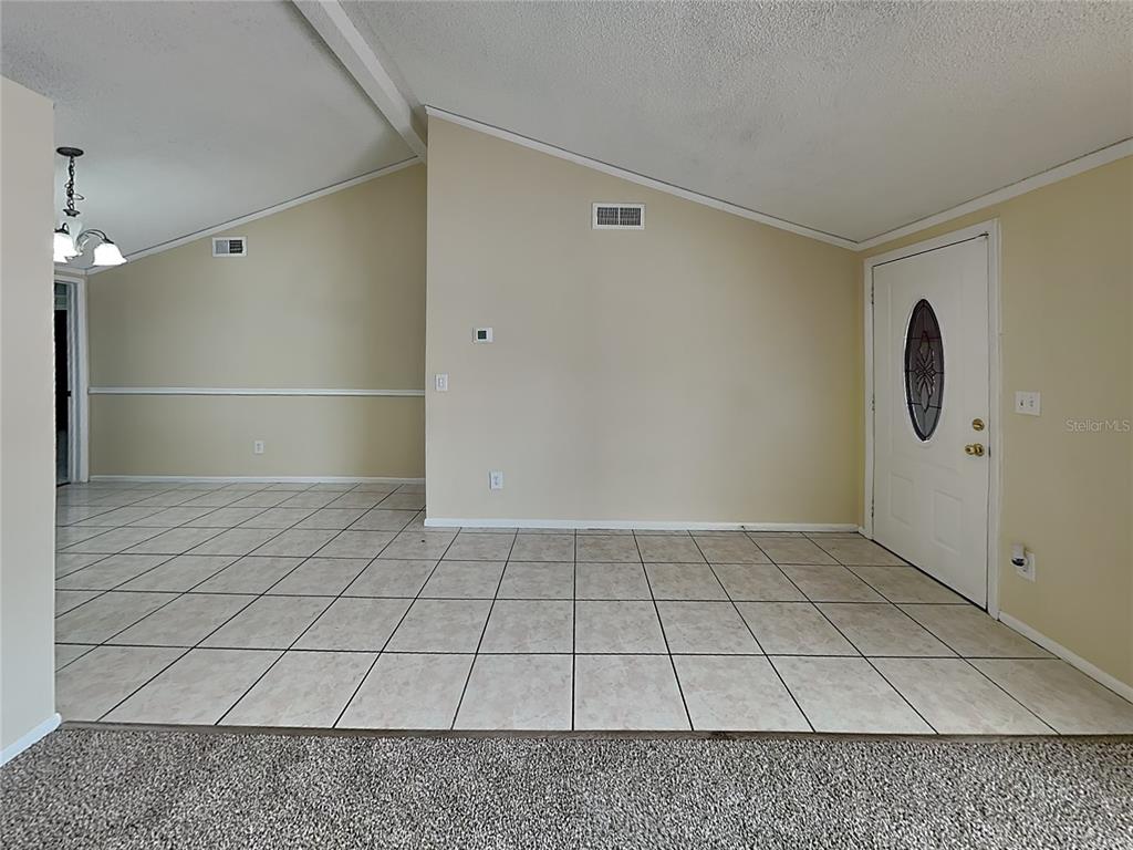 An interior view shows a tiled entryway and dining area with vaulted ceilings and beige walls — 9515 LETTERSTONE COURT, TAMPA, FL