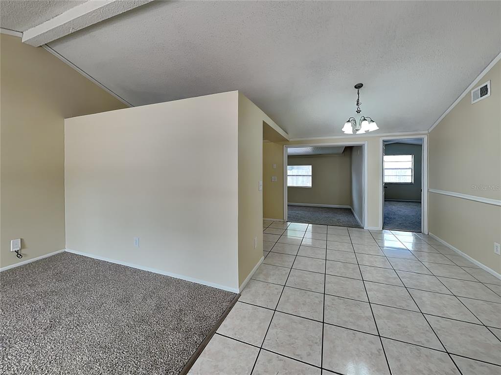 A room with beige walls, a tiled floor, and a carpeted area separated by a wall — 9515 LETTERSTONE COURT, TAMPA, FL