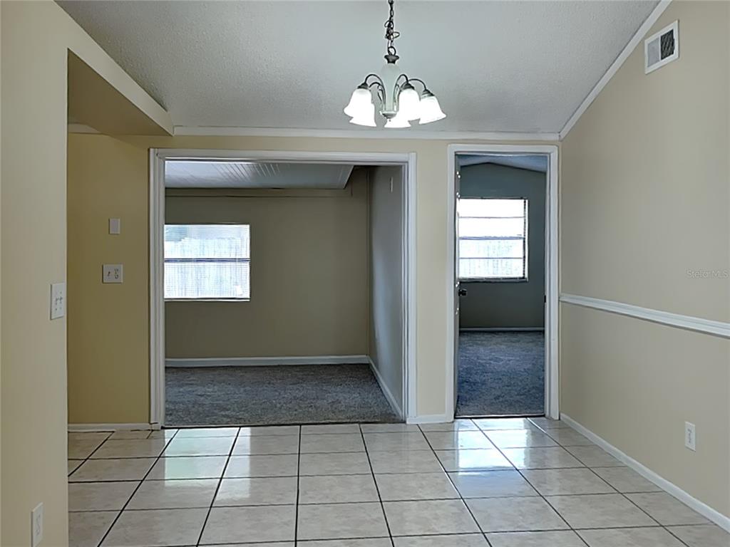A tiled dining area leads to two carpeted rooms through a wide opening and a doorway — 9515 LETTERSTONE COURT, TAMPA, FL