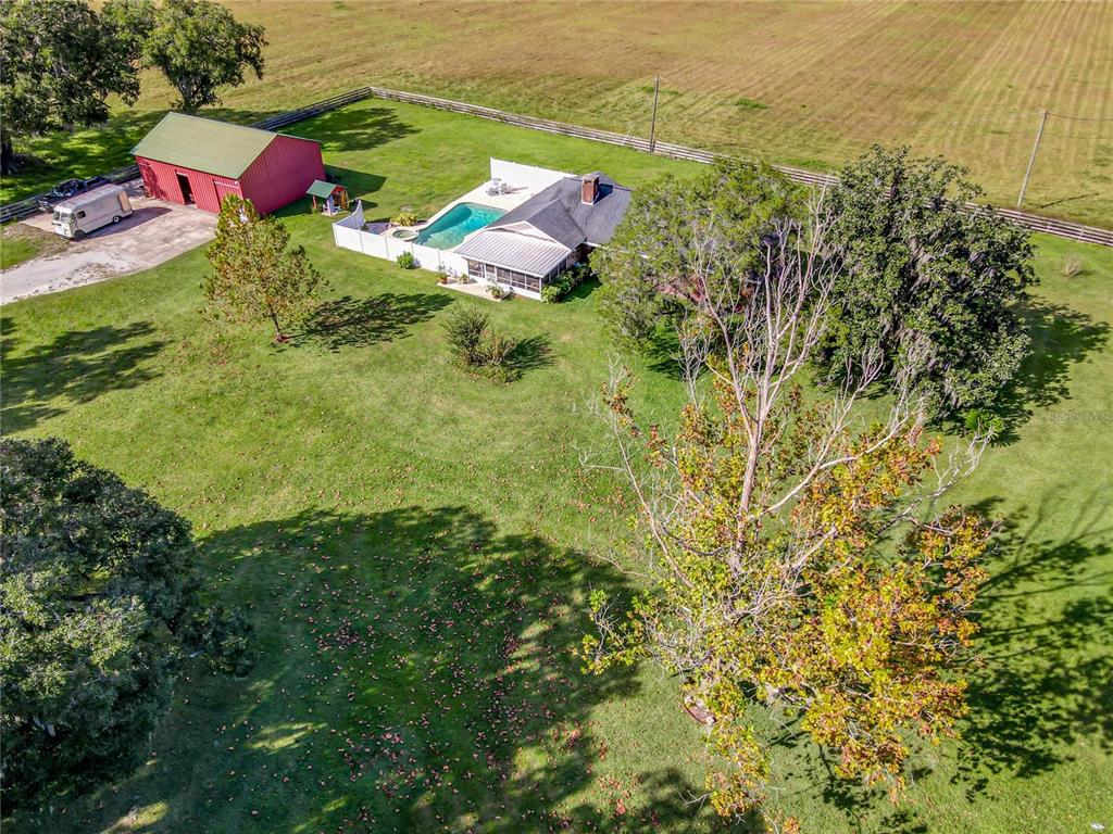 An aerial view shows a house with a pool and a red barn on a lot — 10038 N US HIGHWAY 301, OXFORD, FL